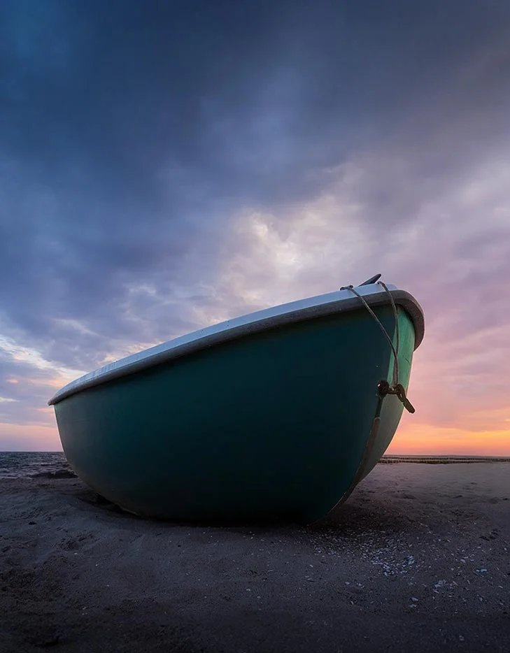 Ein Boot liegt bei Sonnenuntergang am Strand